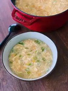 Classic Egg Drop Soup with Corn Served in a bowl with a pot of it in the background