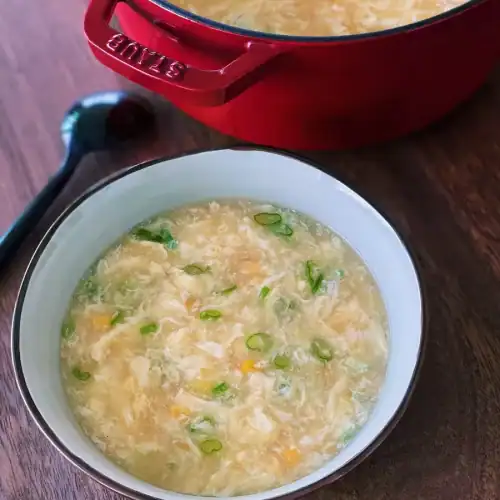 Classic Egg Drop Soup with Corn Served in a bowl with a pot of it in the background