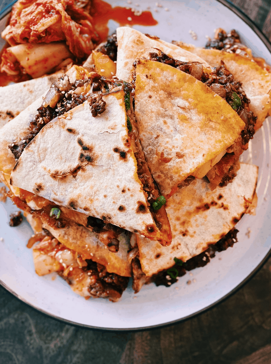 A plate full of Cheesy Asian Fusion Kimchi Bulgogi Quesadillas served with kimchi