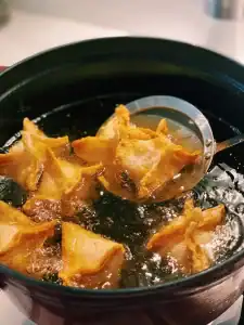 Deep frying crab Rangoons until golden and crispy