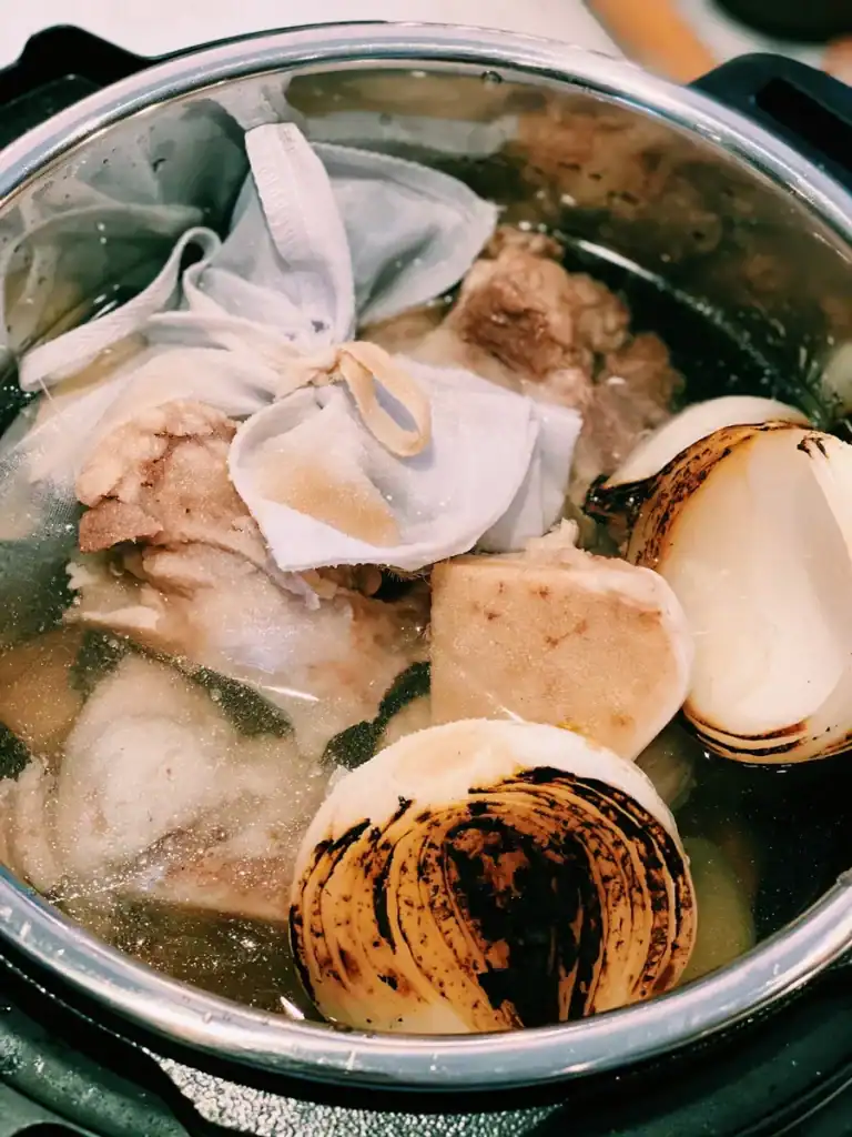 Making Vietnamese Beef Pho Broth in an Instant Pot with beef bones, onion, and spice bag. 