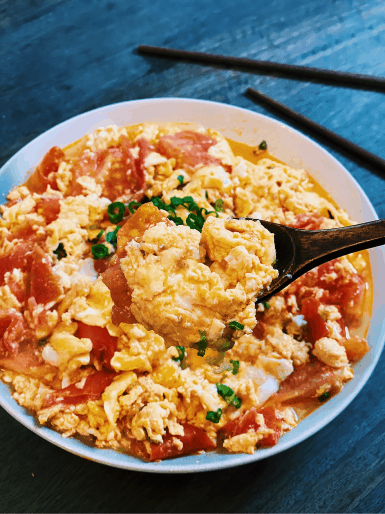 Tomato and Egg Stir-Fry in a plate garnished with green onion mixed together with a spoon