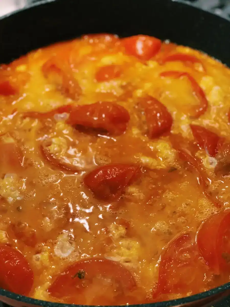 Beaten egg is added to sauteed tomatoes in a pan to make Tomato and Egg Stir-Fry