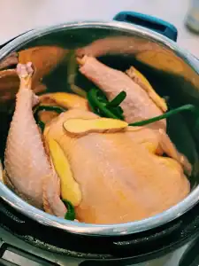 A whole chicken in the instant pot with ginger and scallion for Hainan Chicken Noodle Soup
