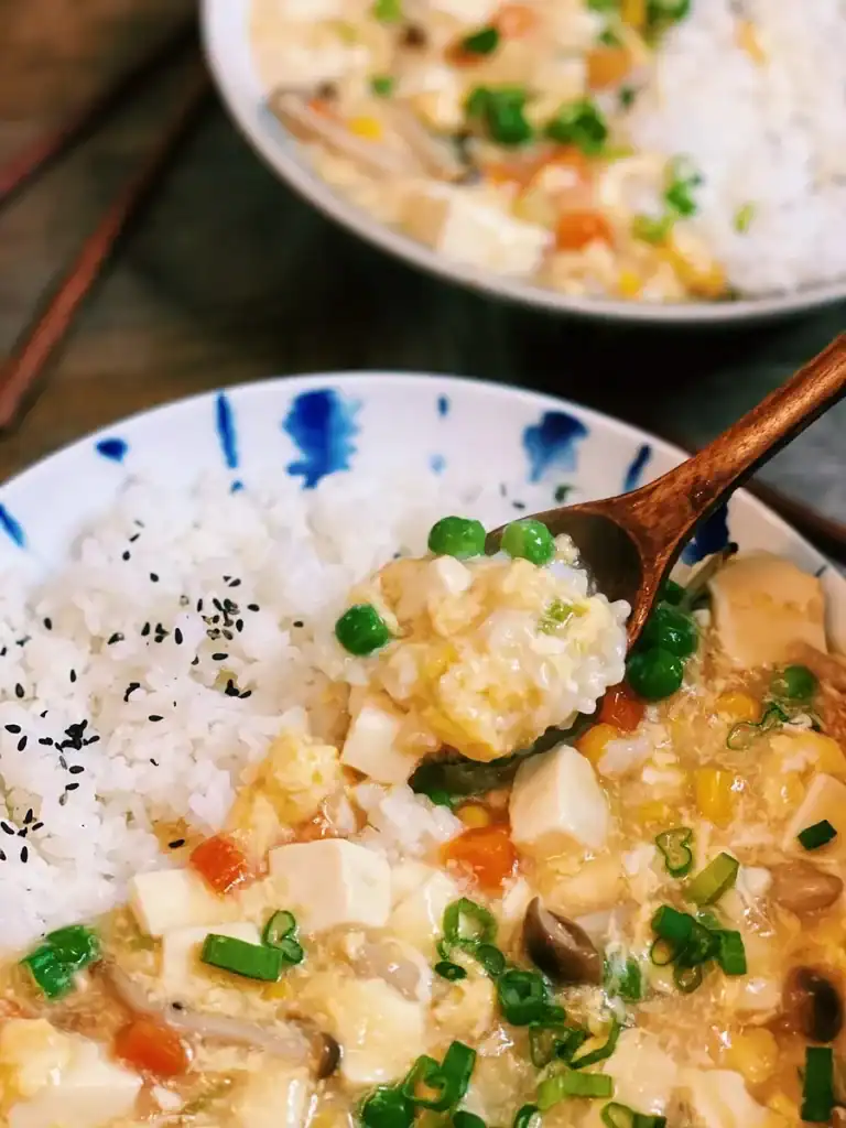 Spooning up a mouthful of Soft Tofu with Silky Egg Sauce Rice Bowl