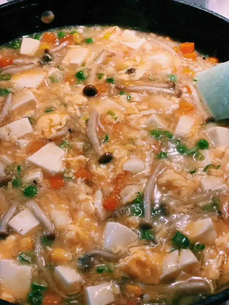 Running a spatula through Soft Tofu with Silky Egg Sauce in a pan to check texture
