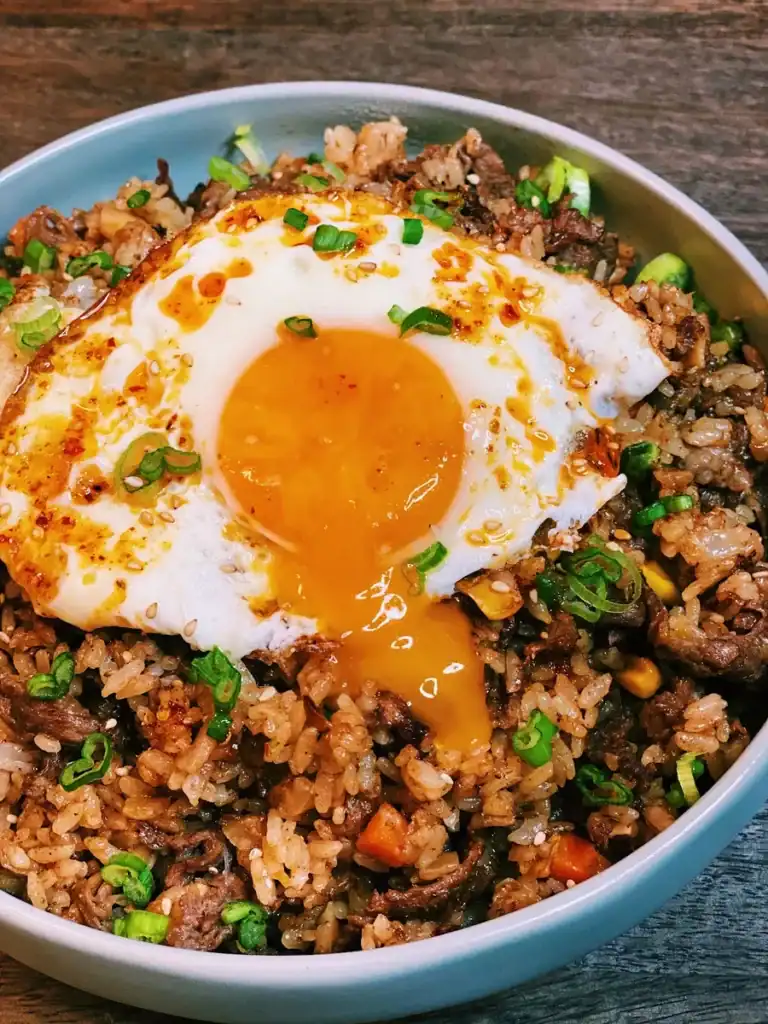 Breaking the fried egg yolk on Taiwanese Shacha Beef Fried Rice