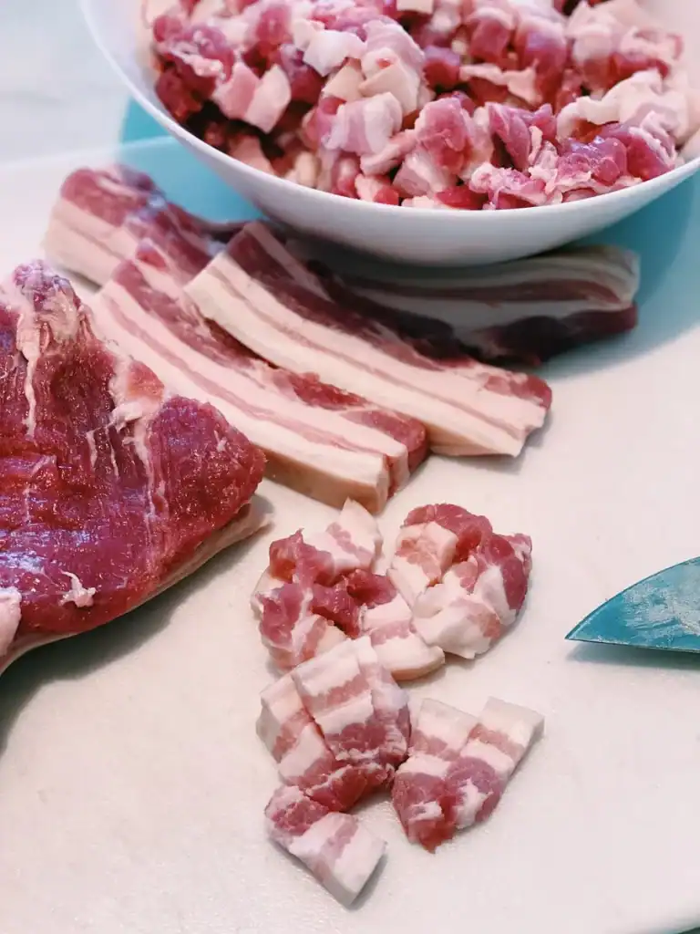 Hand cutting pork belly into tiny appropriately sized layered bites for Taiwanese braised pork rice