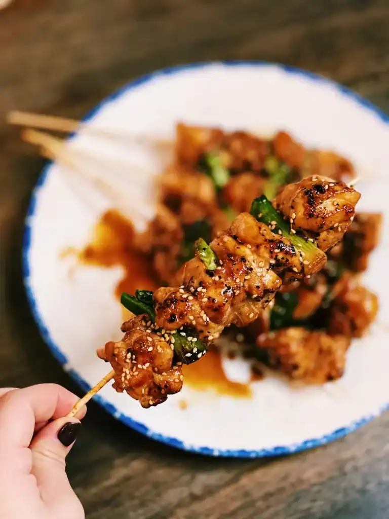 A closeup of one Japanese Chicken Skewer or Yakitori, with the rest of the plate in the background