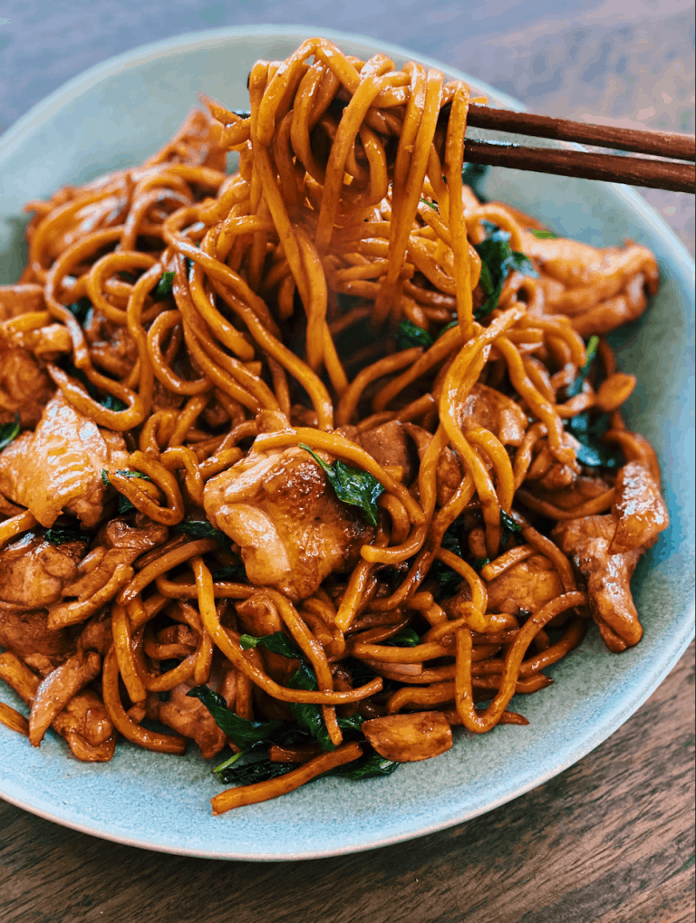 3 cup chicken noodle stir fry served in a plate and picked up with a pair of chopsticks
