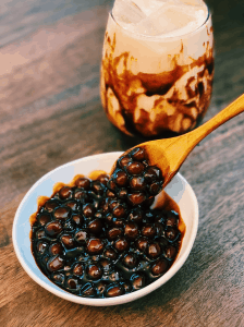 Freshly cooked Brown Sugar Boba with a glass of brown sugar milk in the background.