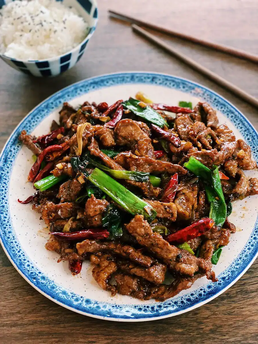 A plate of Mongolian Beef served with a bowl of rice