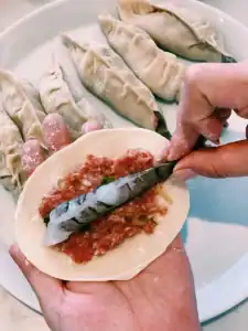 Filling a dumping wrapped with pork filling and a whole shrimp, leaving the tail outside the wrapper for Whole Shrimp Potsticker
