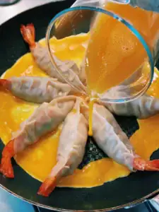 Pouring egg into empty spaces between dumplings for Egg Skirt Whole Shrimp Potstickers