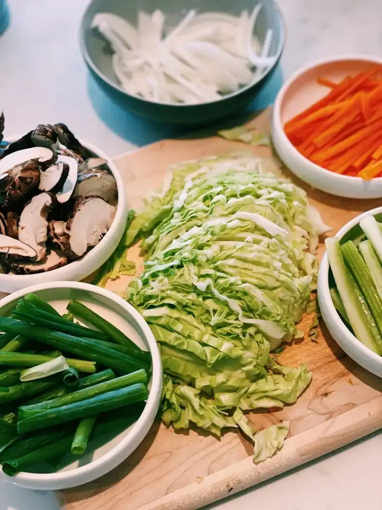 Various chopped vegetables for Vegetarian Chow Mein including green onion, cabbage, onion, carrots, mushrooms, and celery