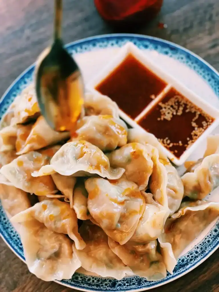 Drizzling homemade chili oil over boiled vegetarian Dumplings