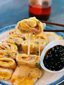 Picking up a piece of Taiwanese Ham and Cheese Egg Pancakes or Dan Bing with a pair of chopsticks