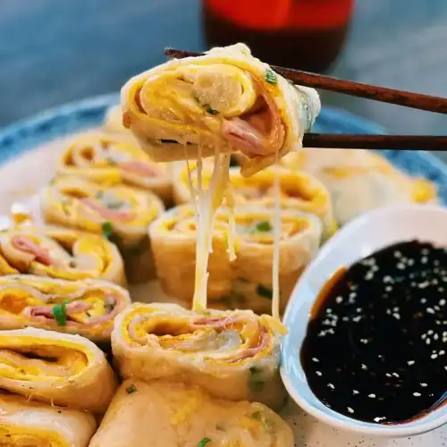 Picking up a piece of Taiwanese Ham and Cheese Egg Pancakes or Dan Bing with a pair of chopsticks