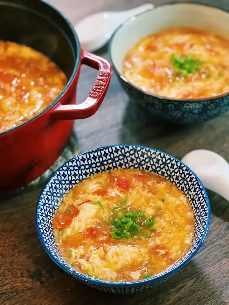 Bowls of tomato egg drop soup garnished with green onions