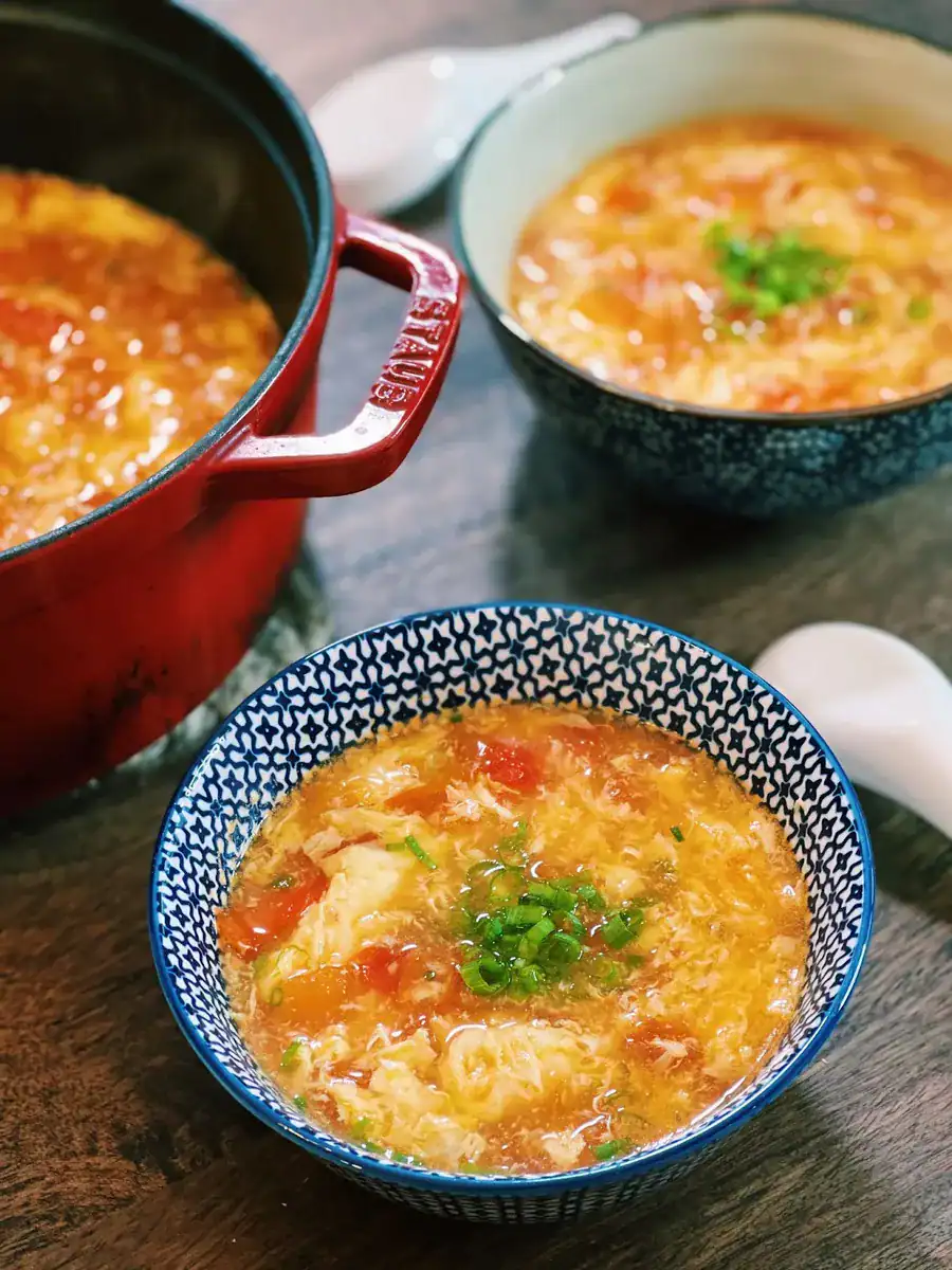 Bowls of tomato egg drop soup garnished with green onions