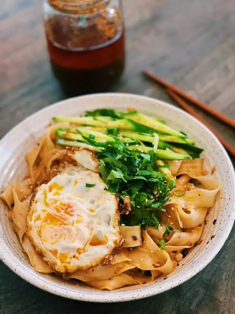 Spicy Garlic Noodles made with homemade chili oil, topped with a fried egg and sliced cucumbers