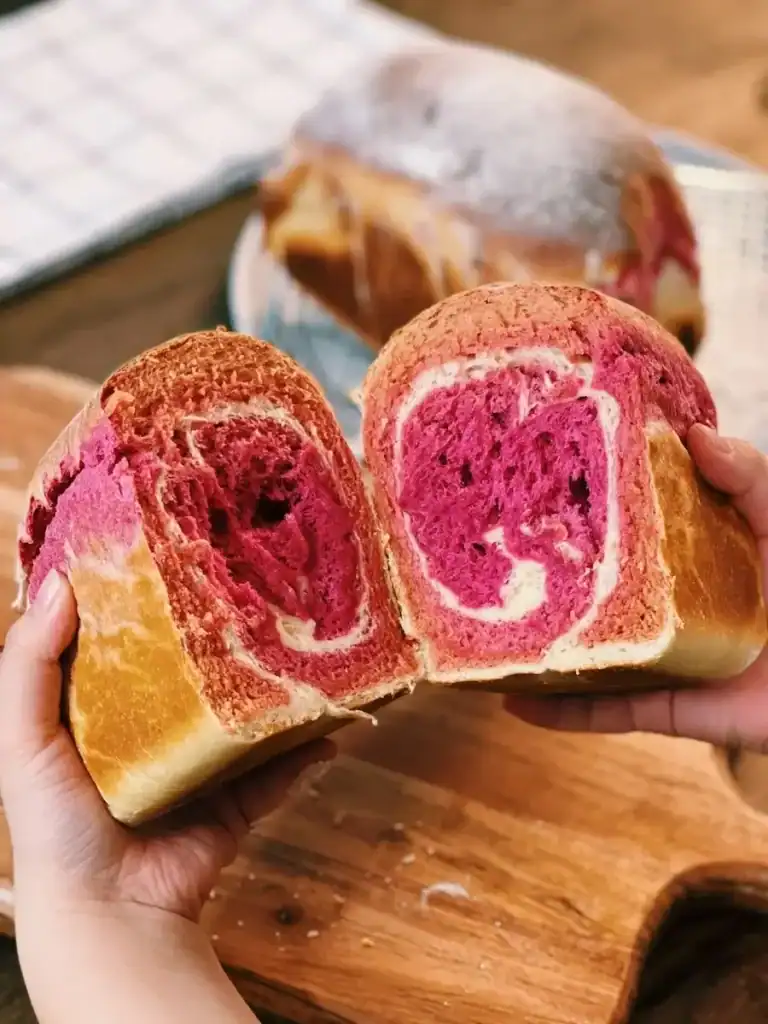 A cross section of freshly baked Beetroot Milk Bread, with swirls of pink and white at the center