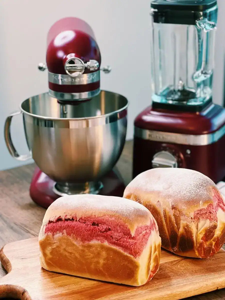 2 loaves of freshly baked Beetroot Milk Bread, with a kitchenaid and a blender in the background