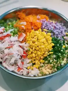 Adding vegetables and mix-ins like carrot, corn, and imitation crab for Hawaiian Macaroni Salad