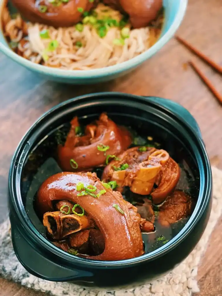 A clay pot of Braised Pork Hock served with noodles on the side