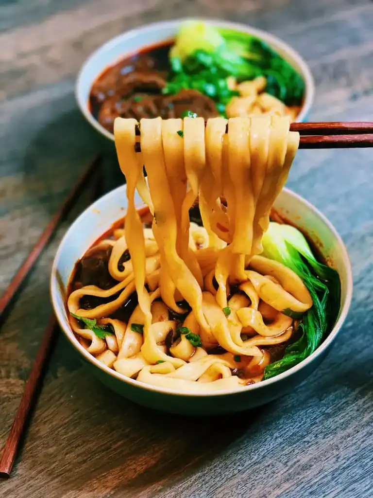 Picking Up Noodles From A Bowl Of Taiwanese Beef Noodle Soup