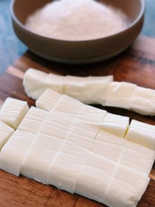 Cutting finished Milk Pudding before covering each bite sized milk dessert in shredded coconut
