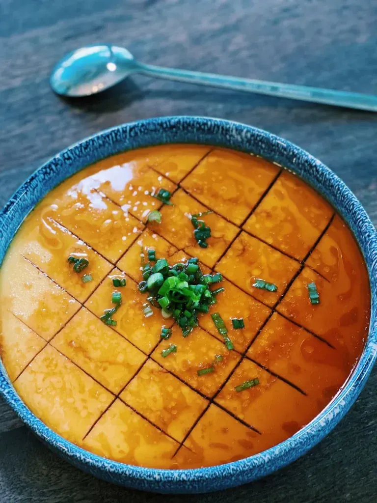 Chinese Steamed Egg topped with sauce and chopped green onions