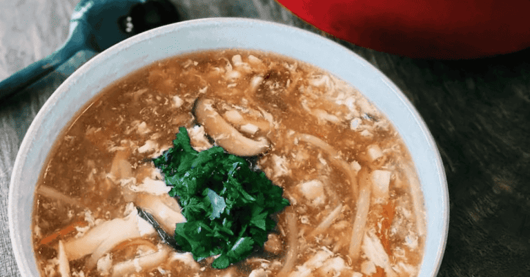 Bowl of Taiwanese Hot and Sour Soup, showcasing a vibrant mix of sliced mushrooms, tofu, bamboo shoots, and a sprinkling of green onions, simmering in a spicy, tangy broth.