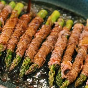 Juicy strips of beef glazed with a savory soy sauce, neatly encircling tender asparagus, cooked to perfection in a skillet