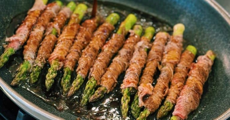 Juicy strips of beef glazed with a savory soy sauce, neatly encircling tender asparagus, cooked to perfection in a skillet