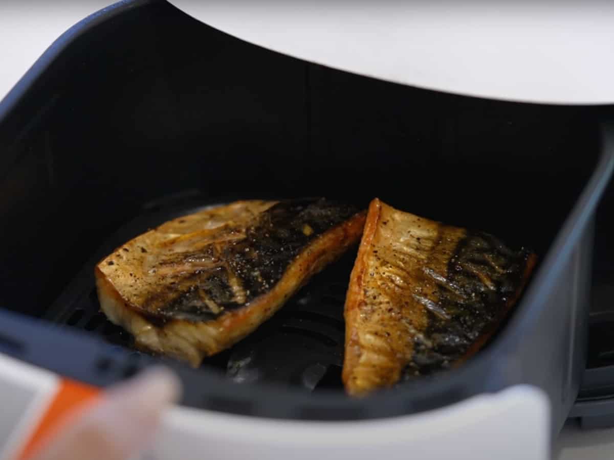 Air fried mackerel coming out of the air fryer, beautifully browned and crispy