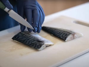 Tiffy cuts slits in the skins of the mackerel filet to prepare for air frying for the air fried mackerel recipe