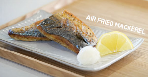 A plate of 2 pieces of air fried mackerel plated with grated daikon and a slice of lemon