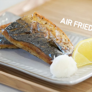 A plate of 2 pieces of air fried mackerel plated with grated daikon and a slice of lemon