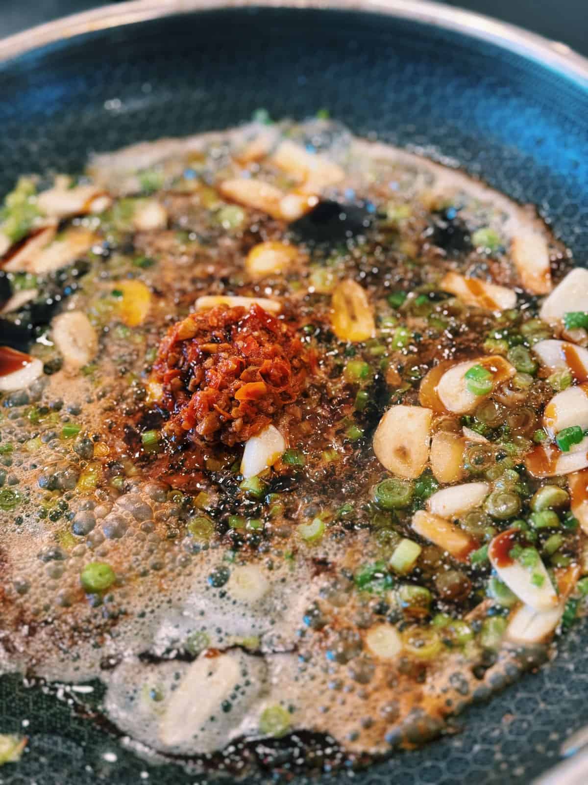 Adding Mama’s Chili Oil into sautéed garlic and scallions for Spicy Chili Oil Vodka Pasta