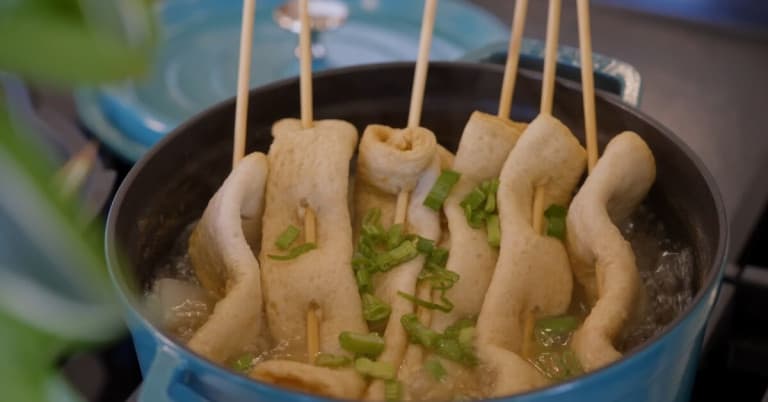 A pot full of Korean Fish Cake Skewer Soup garnished with chopped green onions