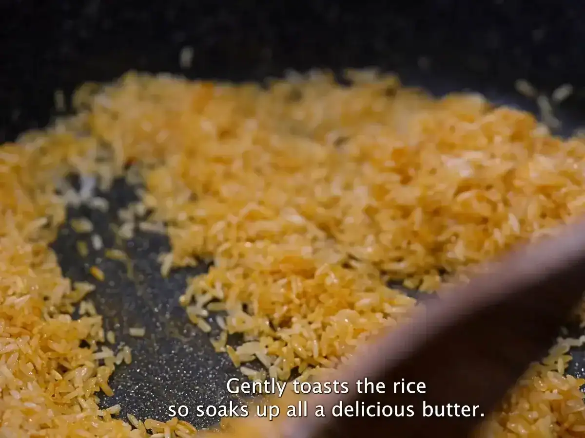 Toasting turmeric, rice, butter, and garlic as a base for turmeric rice.