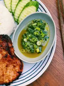 A closeup of a Scallion Sauce to go with your Air Fryer Lemongrass Pork Chop served with cucumber slices and white rice