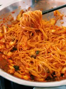Mixing cold cooked noodles with kimchi sauce mix to make Bibim Guksu or Spicy Korean Cold Noodles great for Summer!
