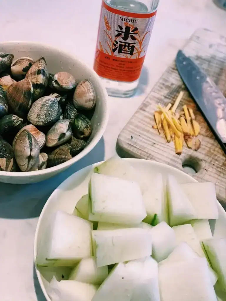 Ingredients for wintermelon steamed clam, including rice wine, ginger, winter melon or wax gourd, and clams 