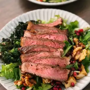 Reverse Seared Steak Sliced and Plated on top of Salad