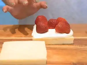 Adding strawberries on top of a piece of bread with fresh whipped cream for Japanese Fruit Sando