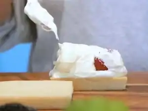 Covering the strawberries with whipped cream on top of a slice of Milk Bread for Japanese Milk Bread