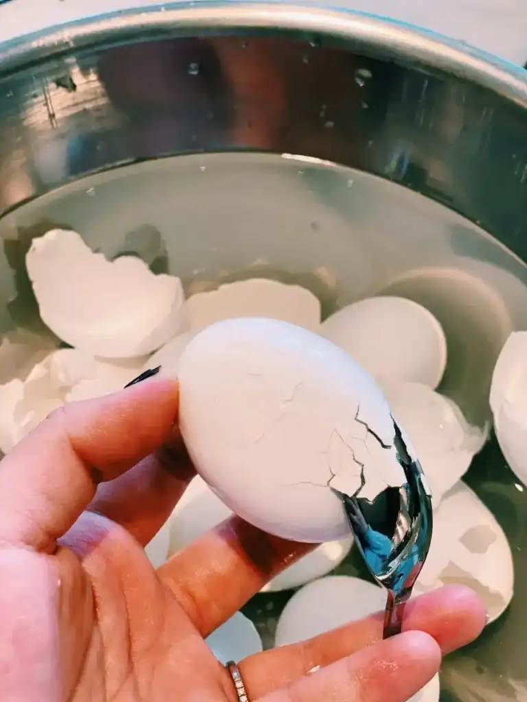 Peeling a soft boiled egg with a spoon for Korean Marinated Eggs or Mayak Gyeran