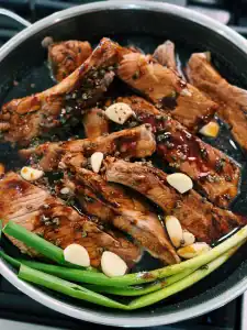 Adding Whole Garlic, Green Onion, and Sichuan Peppercorn into the pot for Chinese Red Braised Pork Ribs